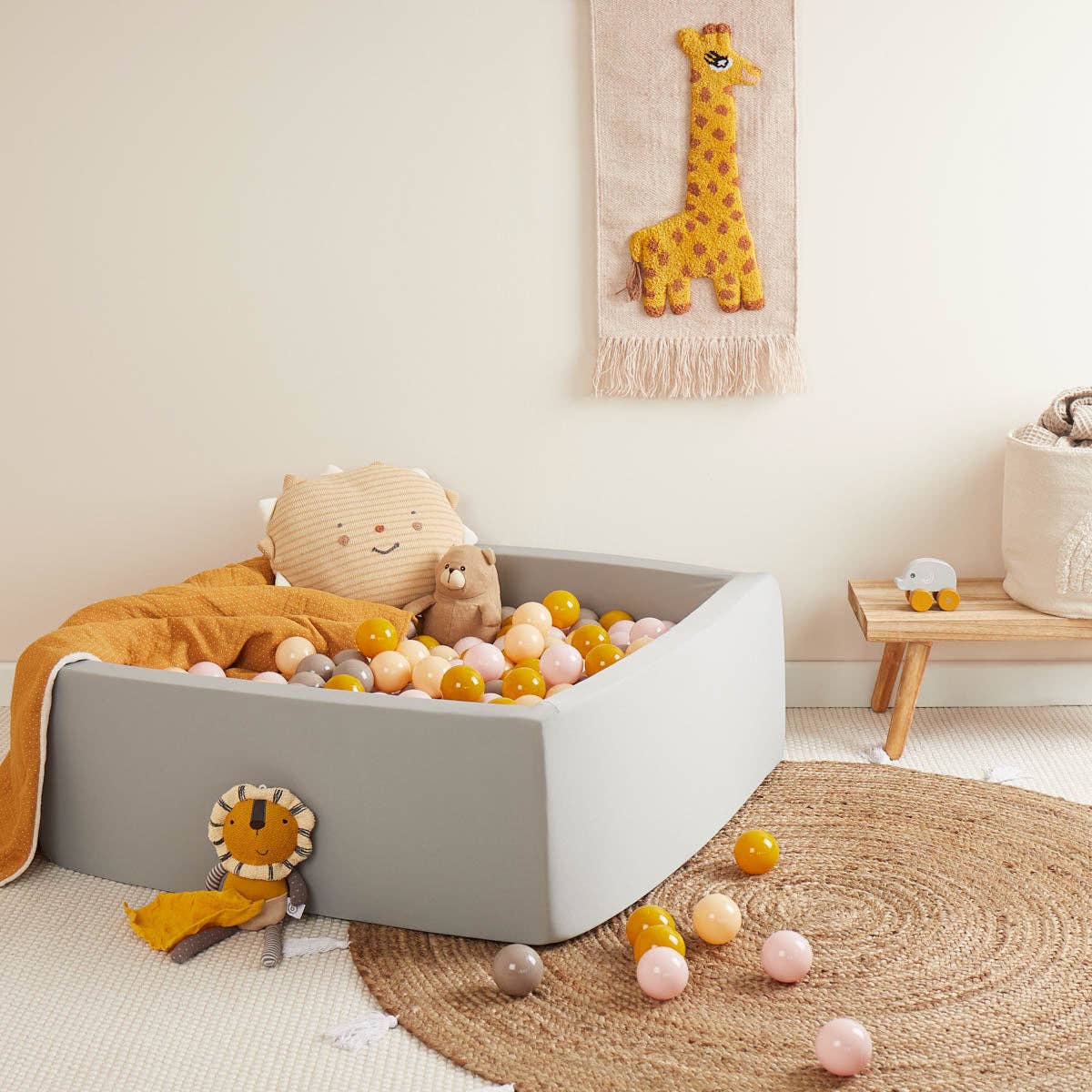 Kinderzimmer mit hellgrauem Bällebad, gelber Decke und bunten Bällen in Rosa, Taupe und Senfgelb.